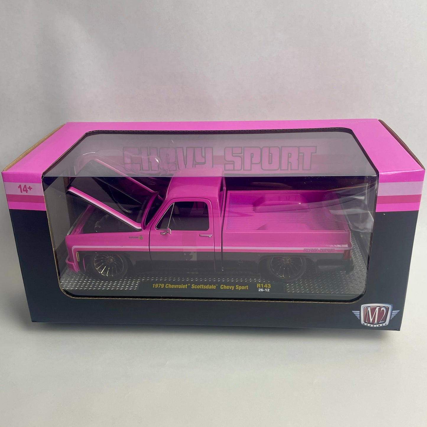A pink diecast model truck in its original packaging, featuring a 1/24 scale Chevy Silverado pickup truck with an open hood and bed. The box has pink and black borders with a clear plastic window.
