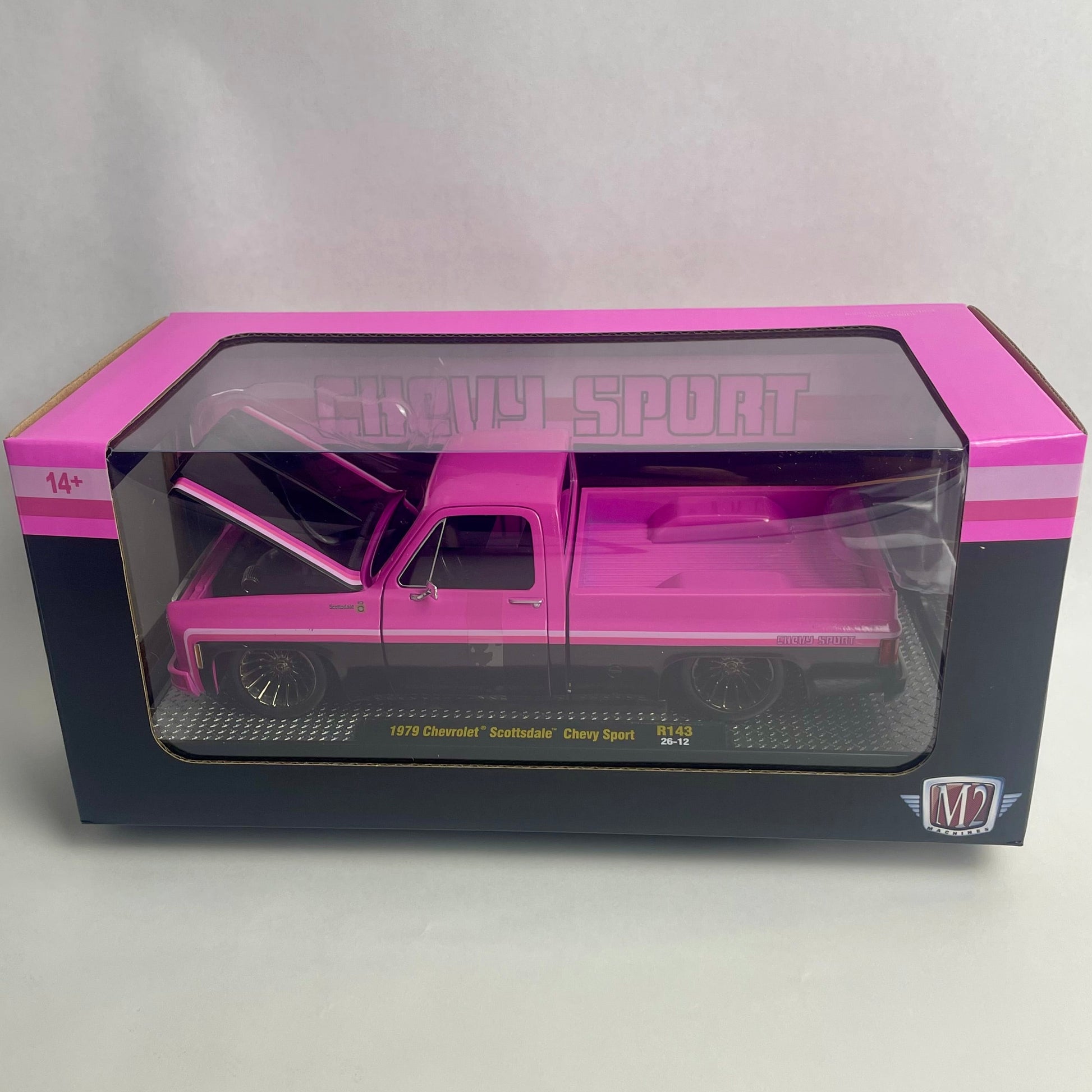A pink diecast model truck in its original packaging, featuring a 1/24 scale Chevy Silverado pickup truck with an open hood and bed. The box has pink and black borders with a clear plastic window.
